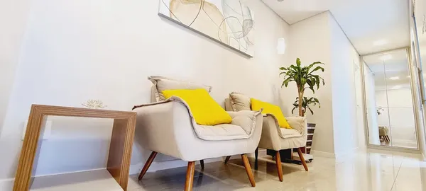 Sala de espera da Dra. Anna Abreu com poltronas ergonômicas e almofadas amarelas para conforto durante espera por tratamentos avancados